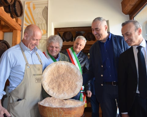 Camporani with four others looking at the opened wheel of cheese.