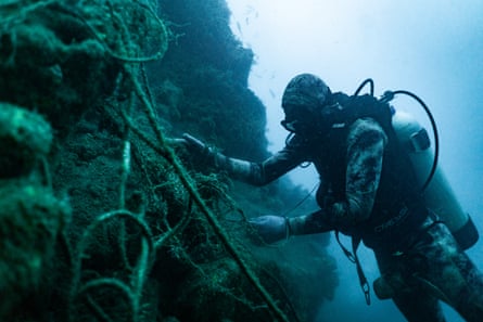 A scuba diver works on a net underwater