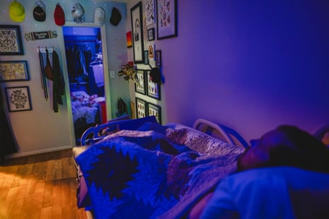 A son sleeping in bed, a mother resting in bed on her phone in the closet under a blue light at night