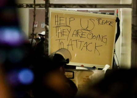 a person holds a sign that reads ‘help us please they are going to attack’