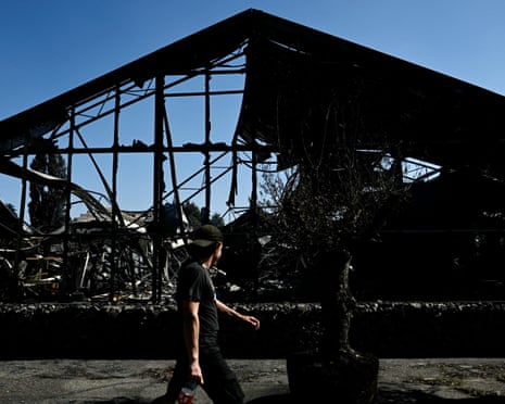 A man walks by a plant nursery destroyed by a wildfire in a business park in Biscarrosse, southwestern France.