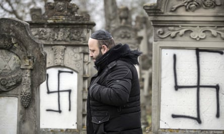A man walks among defaced gravestones at the Jewish cemetery of Herrlisheim, near Strasbourg, eastern France.