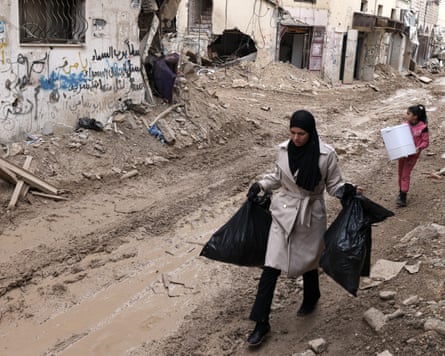 A Palestinian woman and girl carry their belongings along a bulldozed road past damaged buildings in the Jenin camp in March.