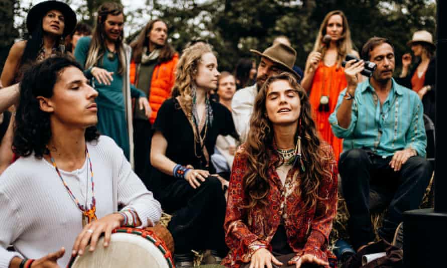 Guests astatine the Medicine festival adjacent Berkshire, UK, instrumentality portion successful a storytelling and opus league astir a occurrence circle, during the daytime.