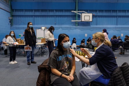 A student in a face mask receiving an injection.