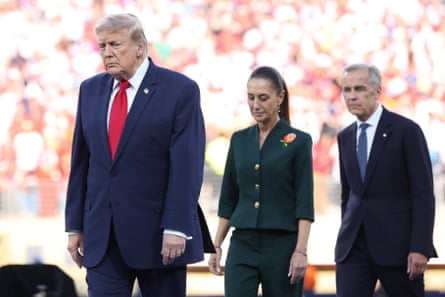 A man in a blue suit walks ahead of a woman and another man