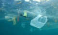 An underwater view of a lot of plastic garbage, including a plastic bag, a plastic bottle and small bits of plastic.