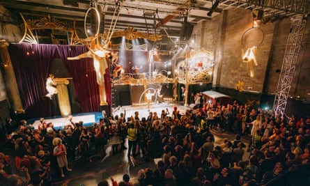 لقطة واسعة للاعبي الجمباز وهم يرتدون الأطواق على المسرح وفوقه، ويشاهدها حشد كبير من الناس