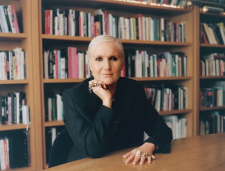 Maria Grazia Chiuri dressed in a black jacket and sitting in front of bookshelves in the Dior offices in Paris.