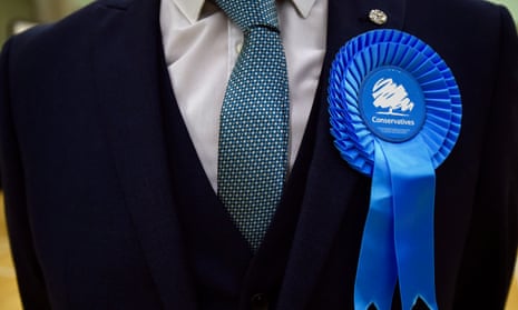 Man in suit wearing Conservative party rosette