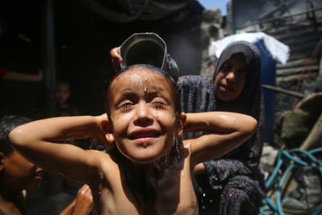 A Palestinian mother showers her child during a heatwave in the southern Gaza Strip in August 2022.