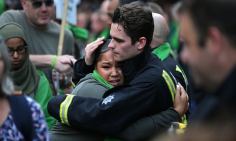 A woman hugs a firefighter during commemorations on the first anniversary of the Grenfell fire in west London on 14 June 2018.