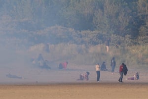 People thought to be migrants emerge from bushes on a beach in Gravelines after French authorities had fired teargas
