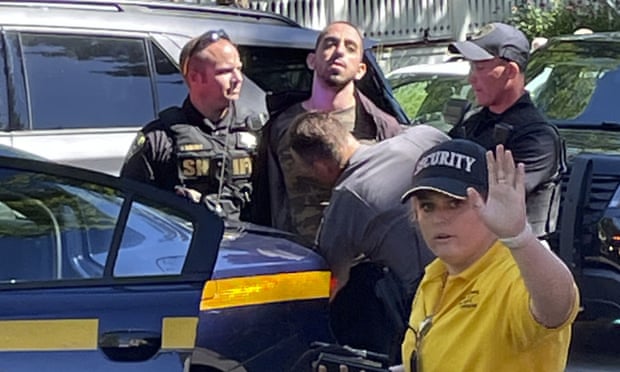 Law enforcement officers detain a person outside the Chautauqua Institution where Salman Rushdie was attacked on Friday.