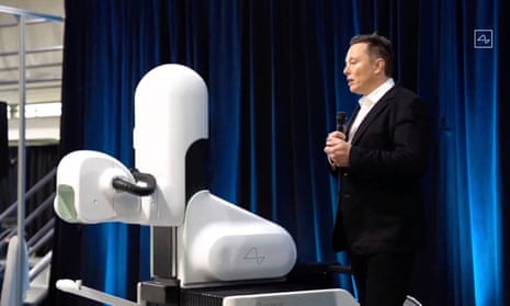 A screengrab showing Elon Musk standing next to a surgical robot during a Neuralink presentation.