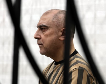 Atef Najib behind black bars and dressed in prison uniform