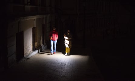 Rusya'nın enerji altyapısına yönelik füze saldırılarından sonra Ukrayna'nın Kiev kentinde insanlar karanlık bir sokakta yürürken telefonlarını meşale olarak kullanıyorlar.