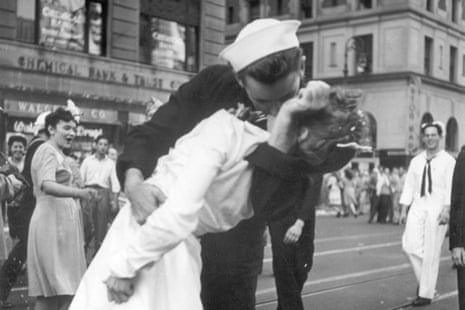 black and white picture of a sailor grabbing a woman in white and kissing her