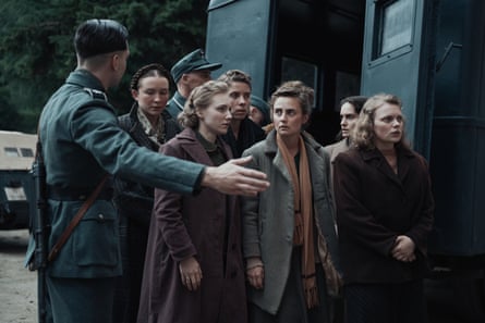 A German officer signals to a group of women.