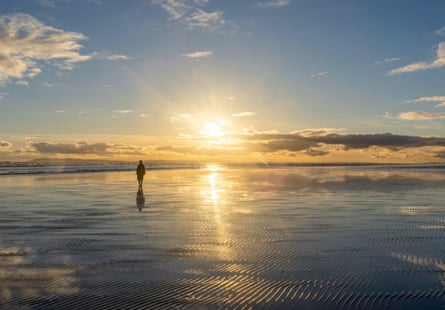 A lone person walks towards sunset at the magnificent West Wittering Beach on the south coast of West Sussex