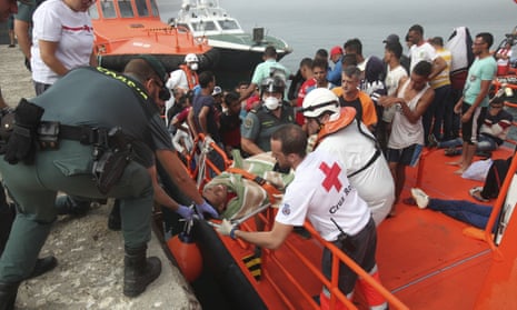 Members of the Spanish Red Cross and Civil Guard help a man off a boat