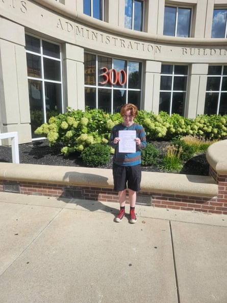 a person holding a paper smiling outside of a state administrative building