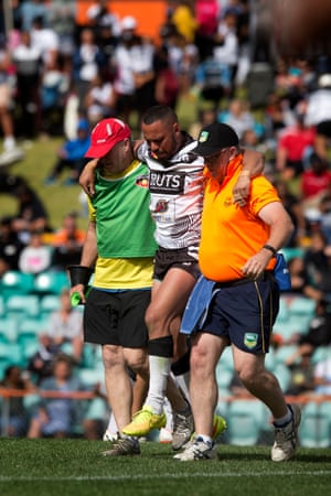 An injured Redfern player is helped from the field