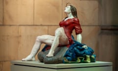 A sculpture of a woman in a red dress giving birth on a rock
