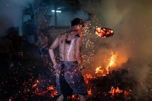 A young man stands as he is hit by burnt coconut husks during the fire fight ritual.