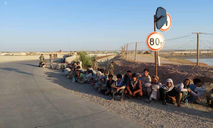 Afghan government soldiers sit at a bridge near the Tajikistan border after fleeing from Taliban advances