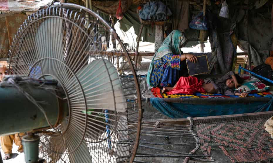 In this May picture from Jacobabad, a woman uses a paper sheet to fan her child amid a power cut during a heatwave. This week, temperatures in the Pakistan city reached over 45C.