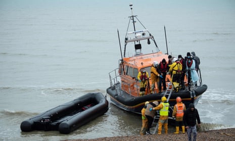 Migrants are helped ashore from an RNLI lifeboat at a beach in Dungeness after being rescued while crossing the Channel in a small boat.