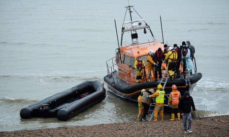People are helped ashore from an RNLI lifeboat at a beach in Dungeness, Kent, after being rescued while crossing the Channel