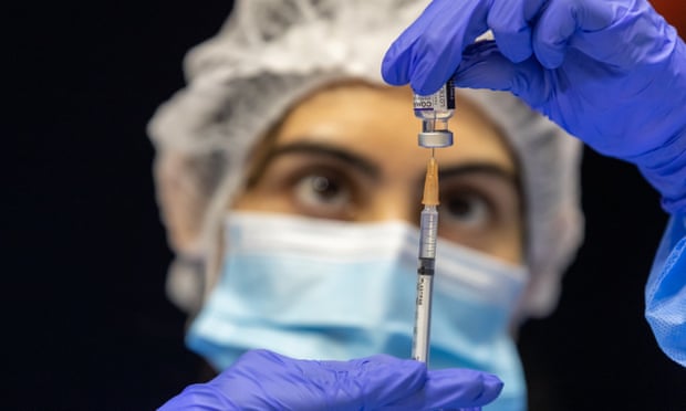 A health care worker fills a syringe with Pfizer vaccine