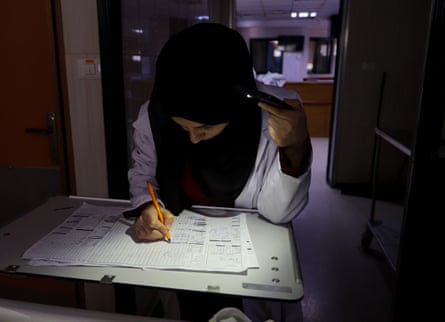 A health worker tries to work in the dark at al-Aqsa Martyrs hospital