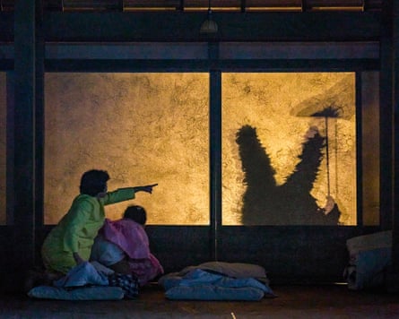 A female actor points at a silhouette on a window.