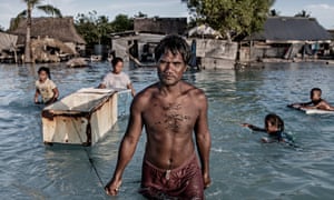 A family wades through sea water that flooded their village in Kiribati central Pacific. Warmer oceans are a major factor in increasing the severity of storms and extreme rainfall.