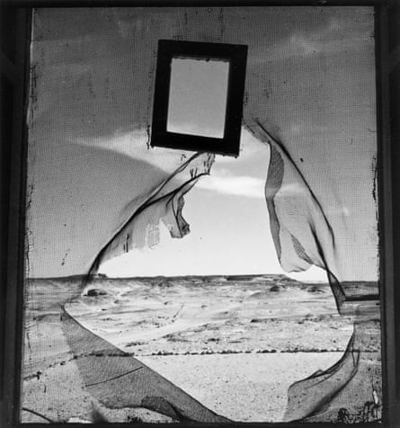 a dry, desolate landscape is seen through a ripped mesh sheath. A small frame is attached to the sheaf just above the centre, and a larger frame surrounds the edge of the image.