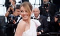 Geri Halliwell-Horner in white dress turns and smiles  with photographers in background.