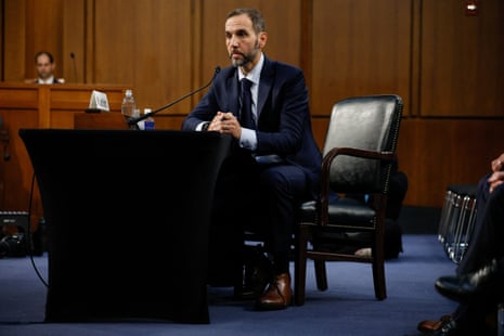 A man sits at a table in front of a microphone