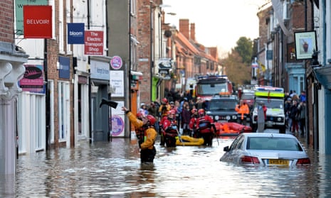 A rescuer throws a Wellington boot to a trapped resident in Walmgate, York, after the rivers Foss and Ouse burst their banks. 
