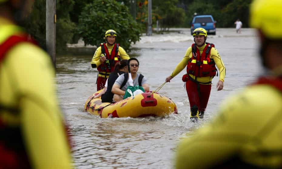 Queensland Fire and Emergency Services crew members use an inflatable boat to pull residents through floodwaters at Hermit Park in Townsville