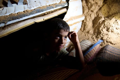 Mohammed Abu Ganima, 7, peers out of a makeshift shelter in his Bedouin village: a minibus buried in the earth to try to protect his family from incoming Iranian fire, in the Negev Desert in southern Israel, early Wednesday, June 18, 2025.