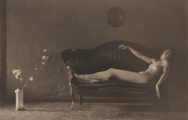 A fluid, languid nude, artfully draped across a couch, with a beautifully Japanesque ikebana flower and vase arrangement in the left-hand corner for balance.