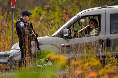 Police officers stop to question a driver at a roadblock, Thursday, Oct. 26, 2023, in Lisbon, Maine, during a manhunt for the suspect of Wednesday's mass shootings.