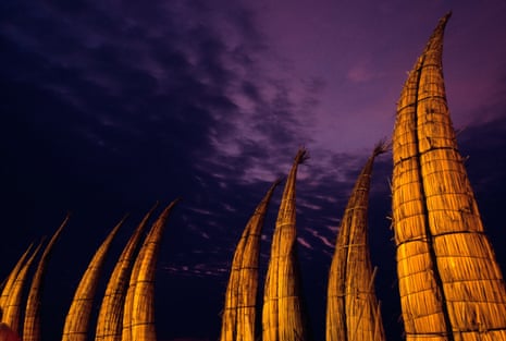 Curved boats on end against a purple night sky.