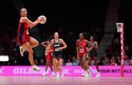 Jess Shaw jumps holding the ball to her side as other players run towards her