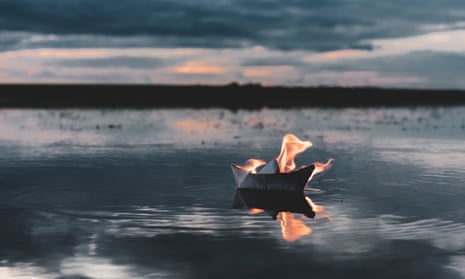 White paper boat on fire floating in the river at sunset