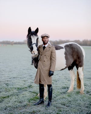 a man in a trench coat with a horse in a field