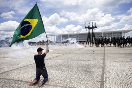 A demonstrator holds a Brazilian national flag in front of mounted police during a protest outside Planalto Palace.